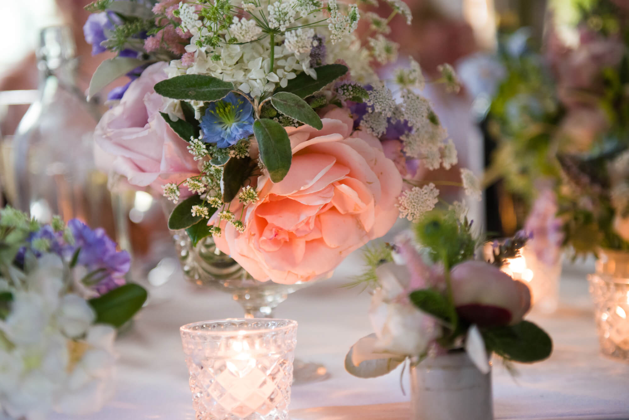 peach roses and cow parsley on a wedding table at voewood house in norfolk