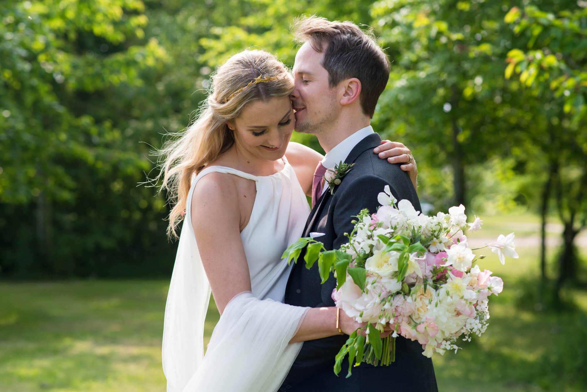 bride and groom in an embrace with bouquet by rowan blossoms