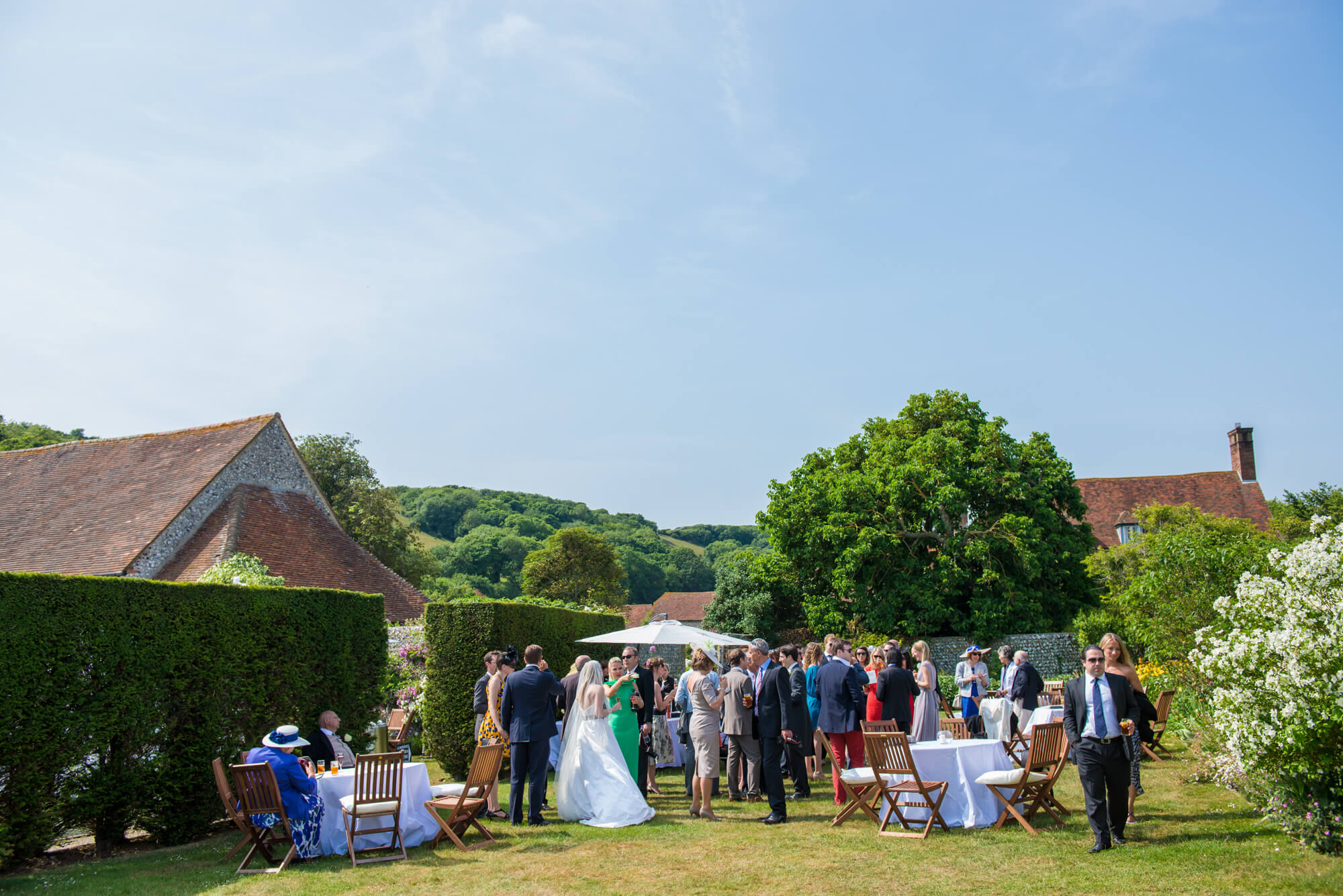 Wedding guests enjoying the celebrations in the gardens of Birling Manor