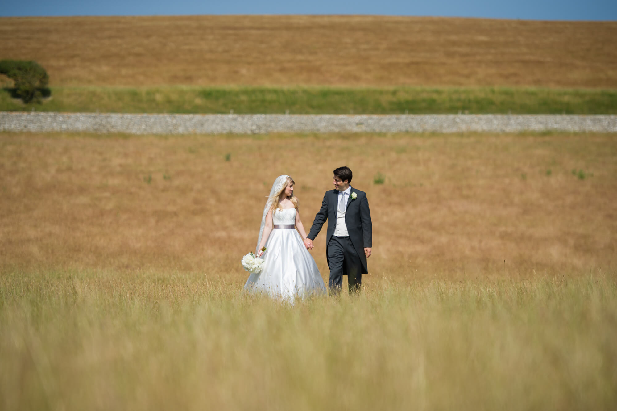 A bride and groom holding hands in the Sussex countryside