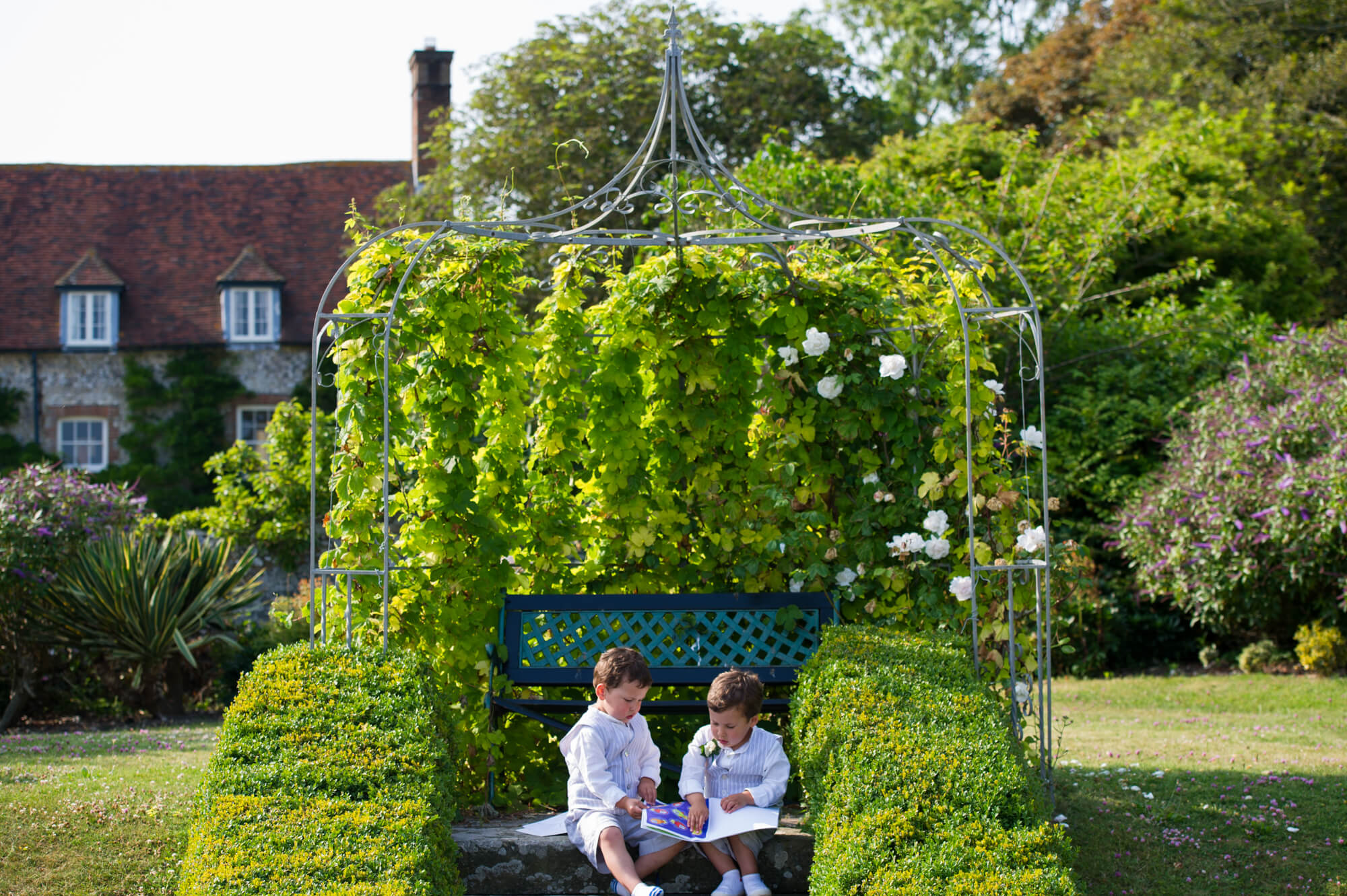 Pageboys sitting on a bench in the gardens of Birling Manor House