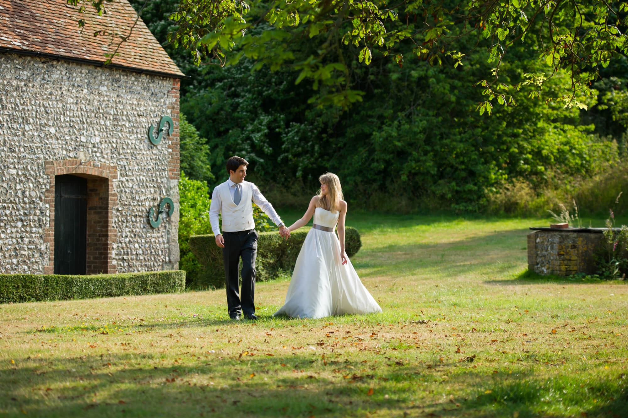 A bride and groom walking in the grounds of Birling Manor in Sussex