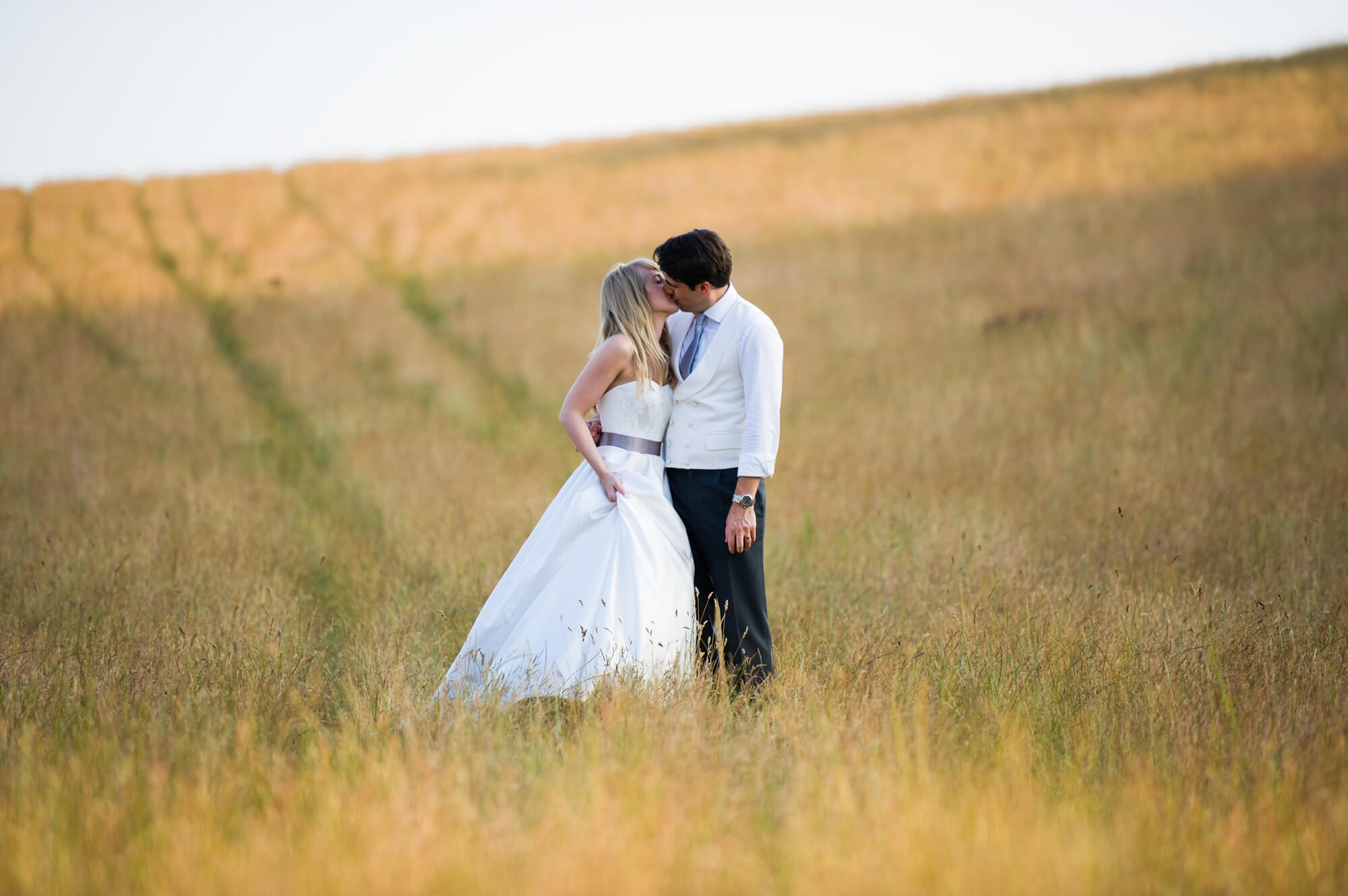 A bride and groom kissing in a field in the Sussex countryside