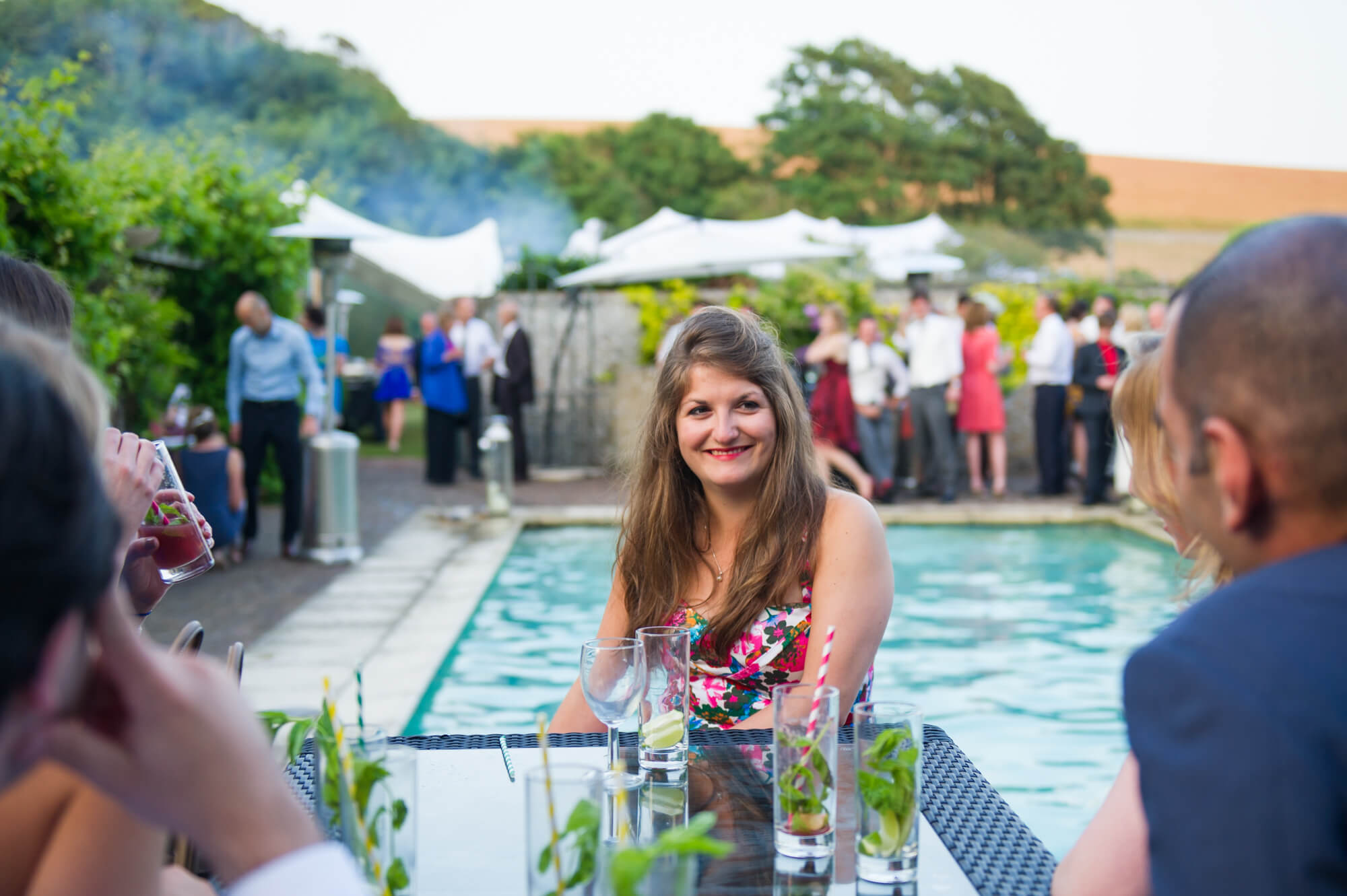 Wedding guests sitting at a table next to the swimming pool at Birling Manor in Kent