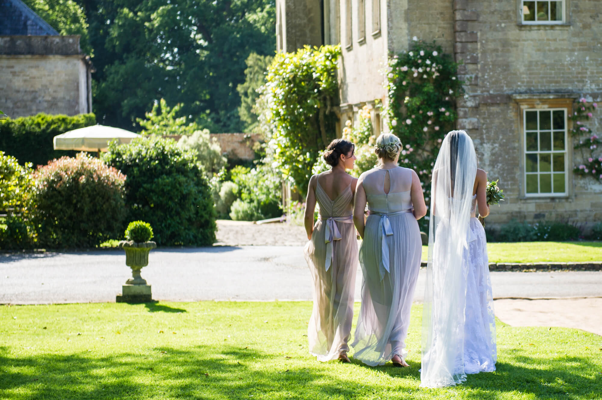 bride and bridesmaids walking across the lawn at babington house