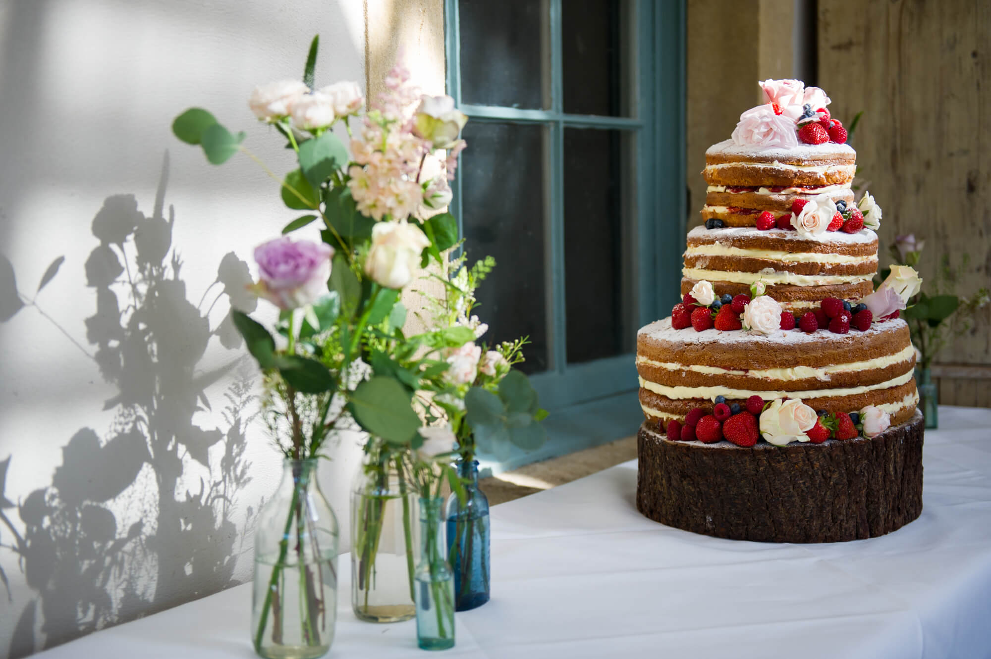 naked wedding cake decorated with strawberries and flowers at babington house