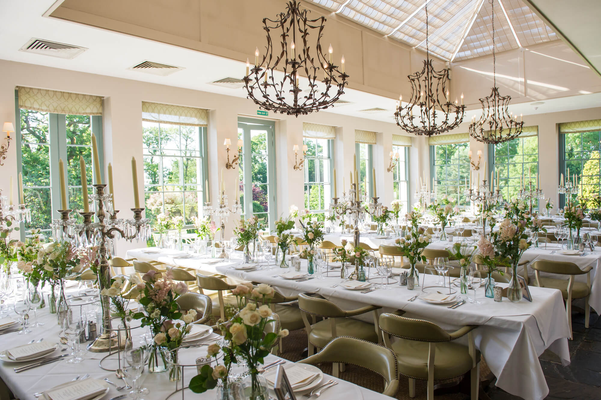 the orangery at babington house ready for a wedding breakfast with pretty flowers and candles