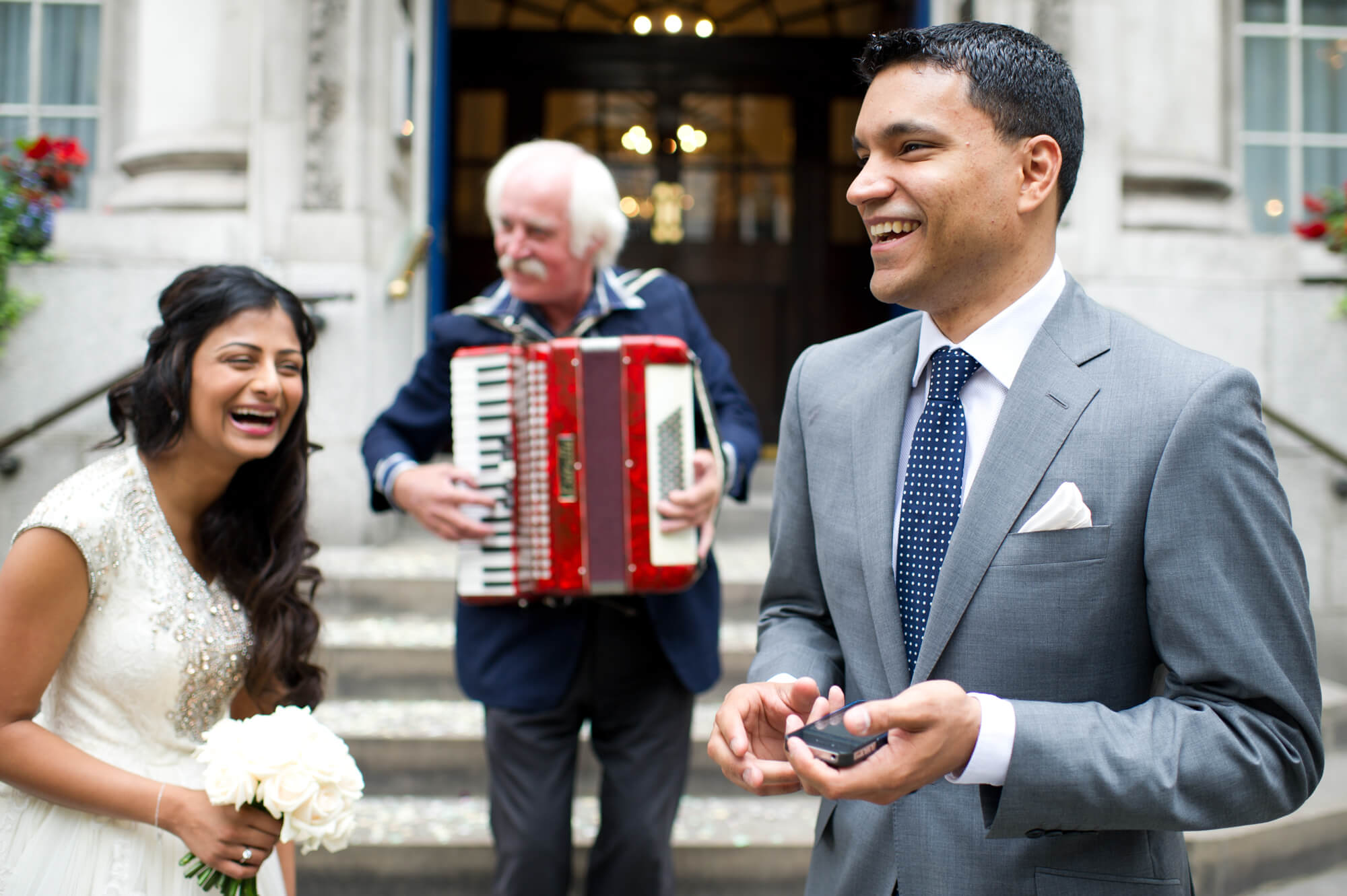 A man playing an accordion on the steps at Chelsea Town Hall