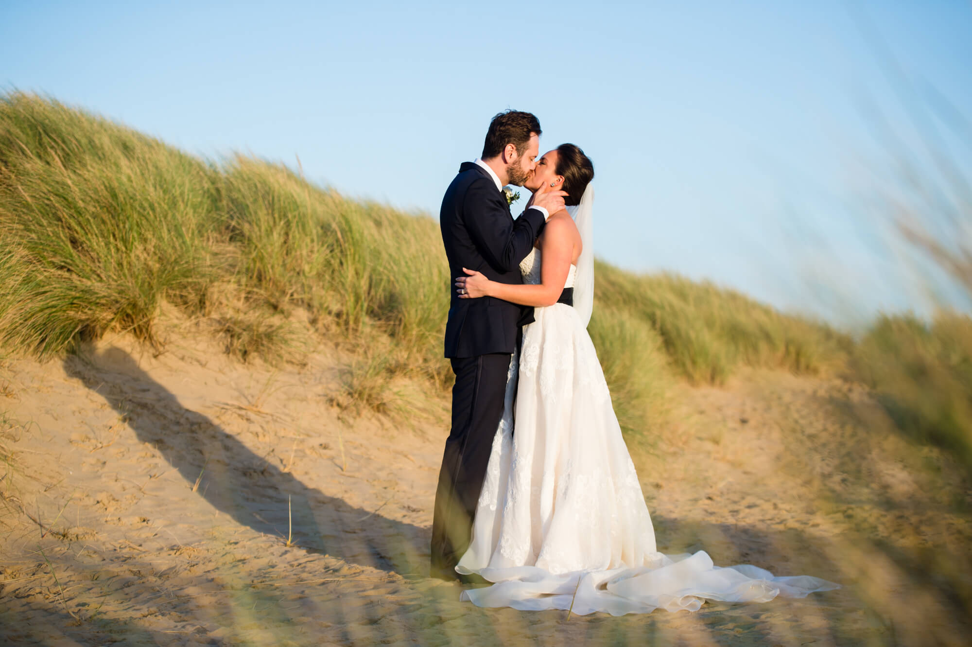 A newly married couple kissing on the beach at camber sands
