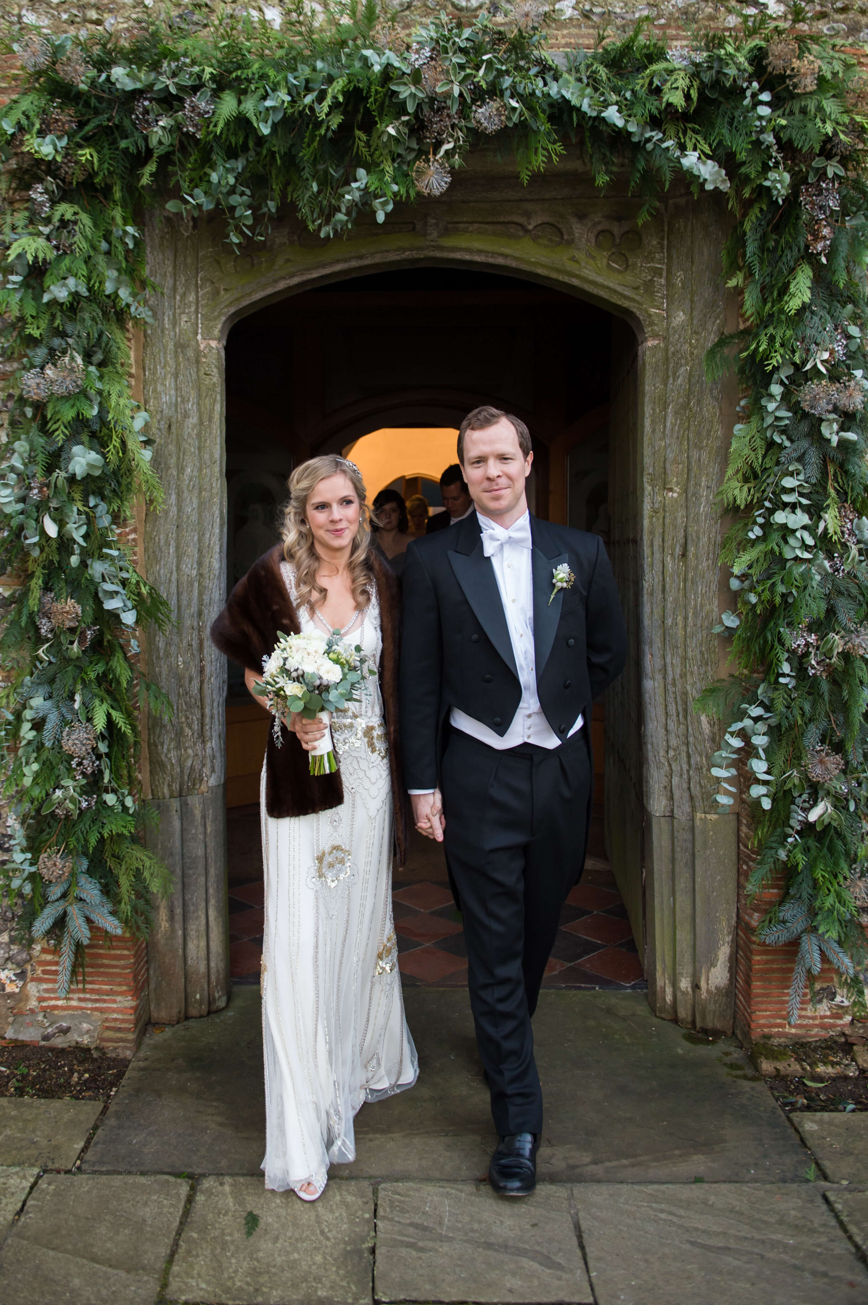 The bride and groom leaving the chapel under a floral arch