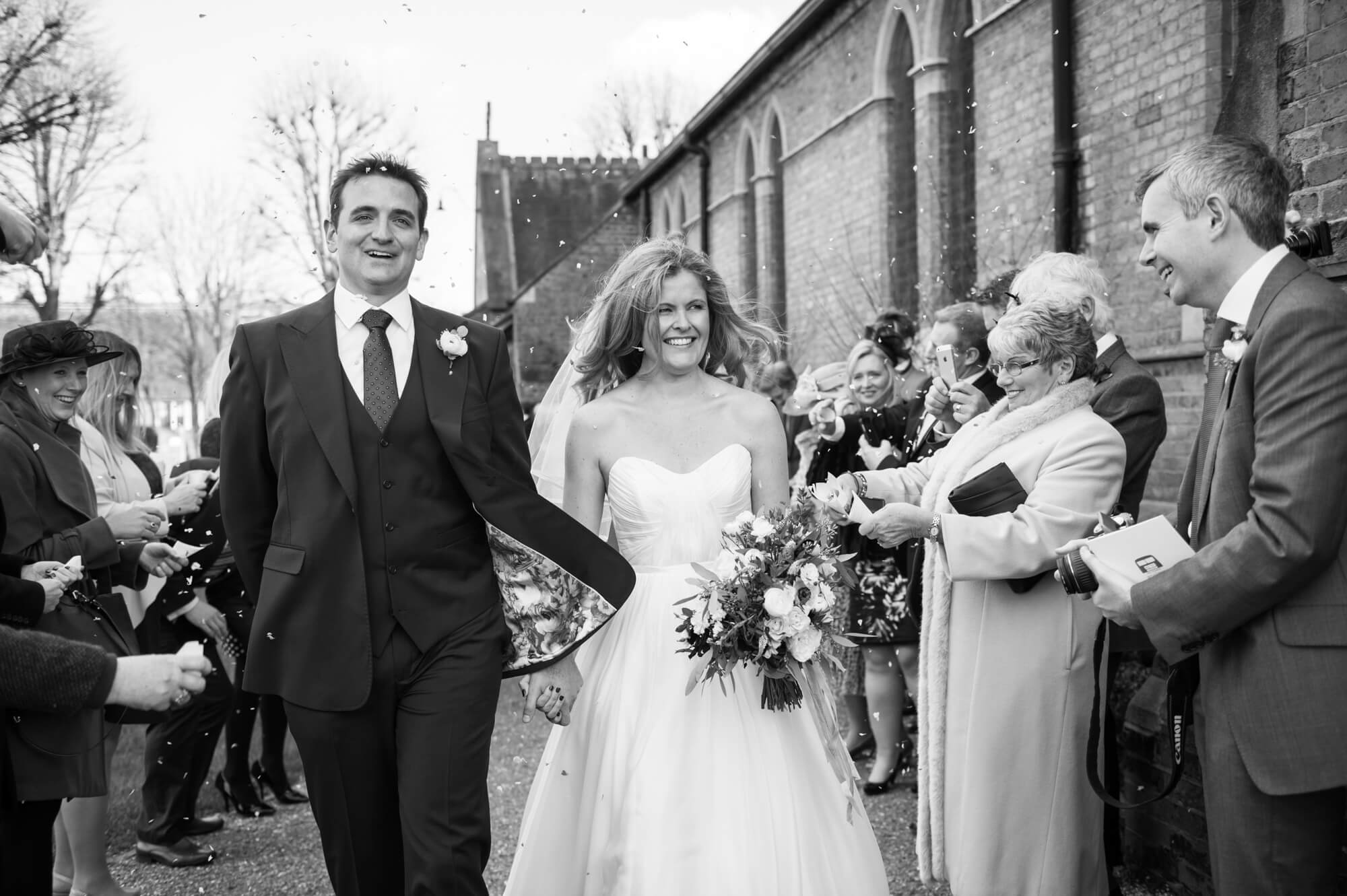 bride and groom walking through confetti outside of st marys church in putney photograph taken by especially amy