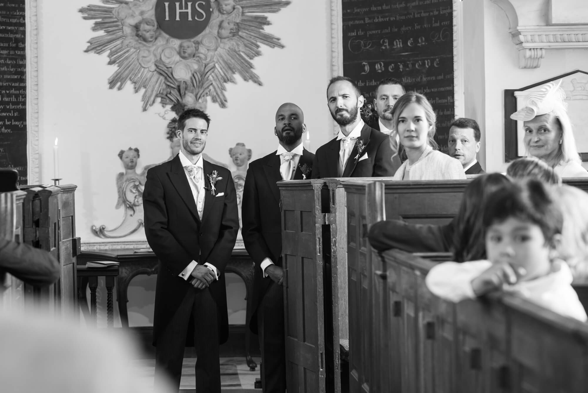 groom and ushers watching the bride enter at babington house chapel
