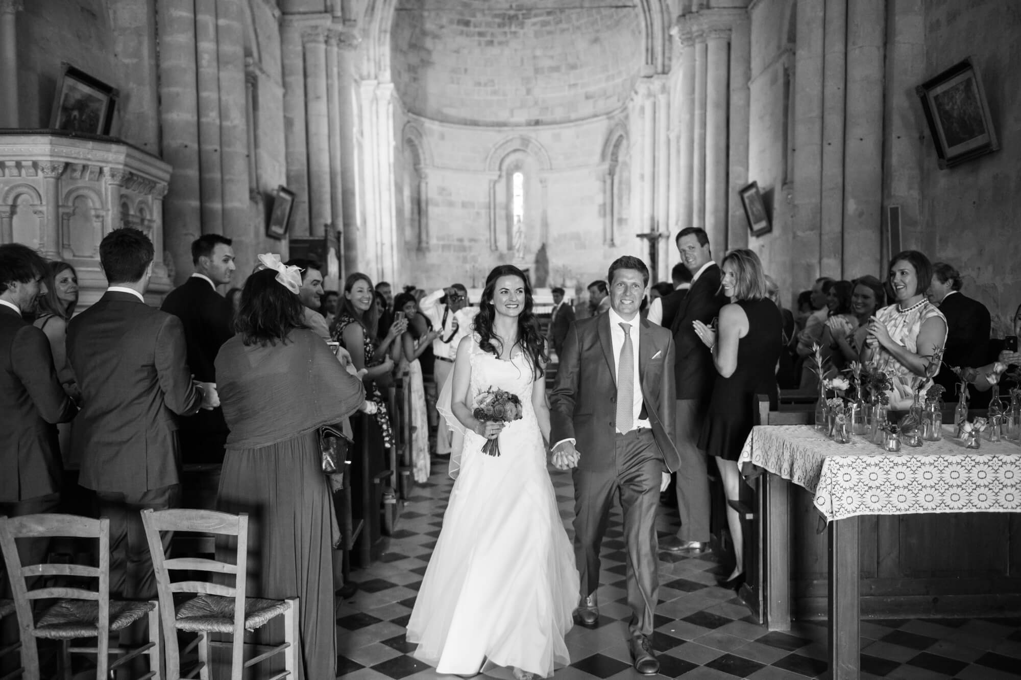 bride and groom walking down the aisle at a church near st emillion