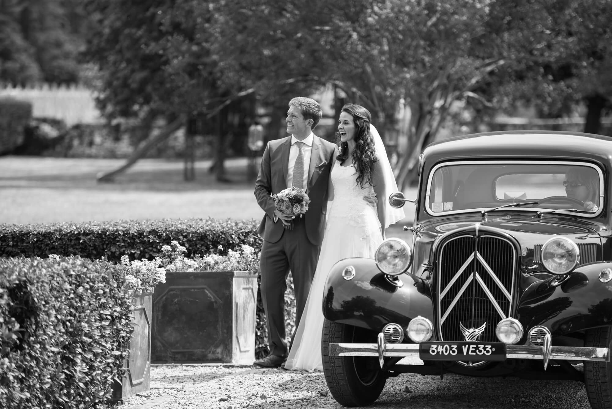 bride and groom standing next to a vintage french wedding car at chateau rigaud