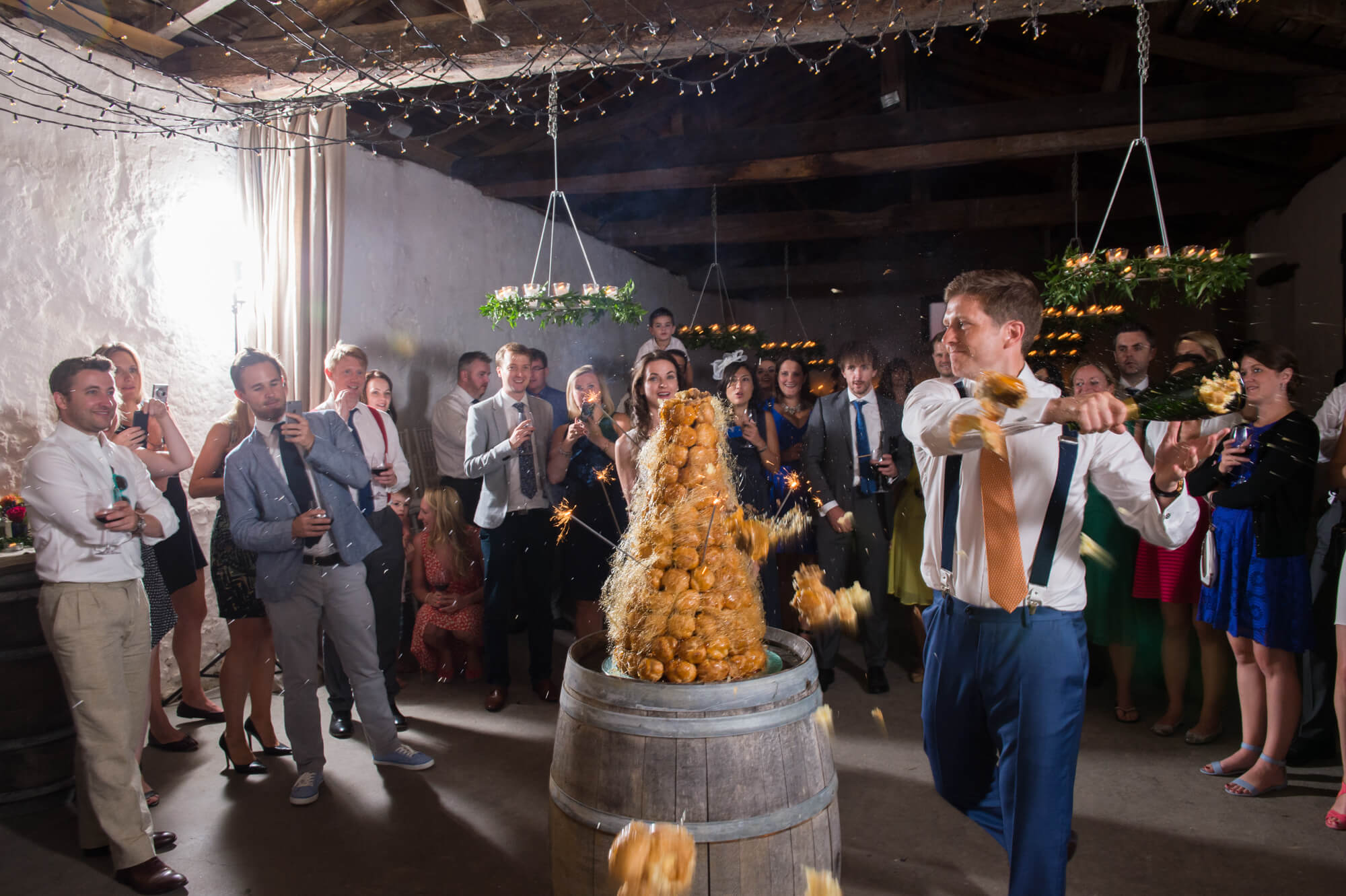 groom hitting the top of the croquembouche with a champagne bottle at chateau rigaud