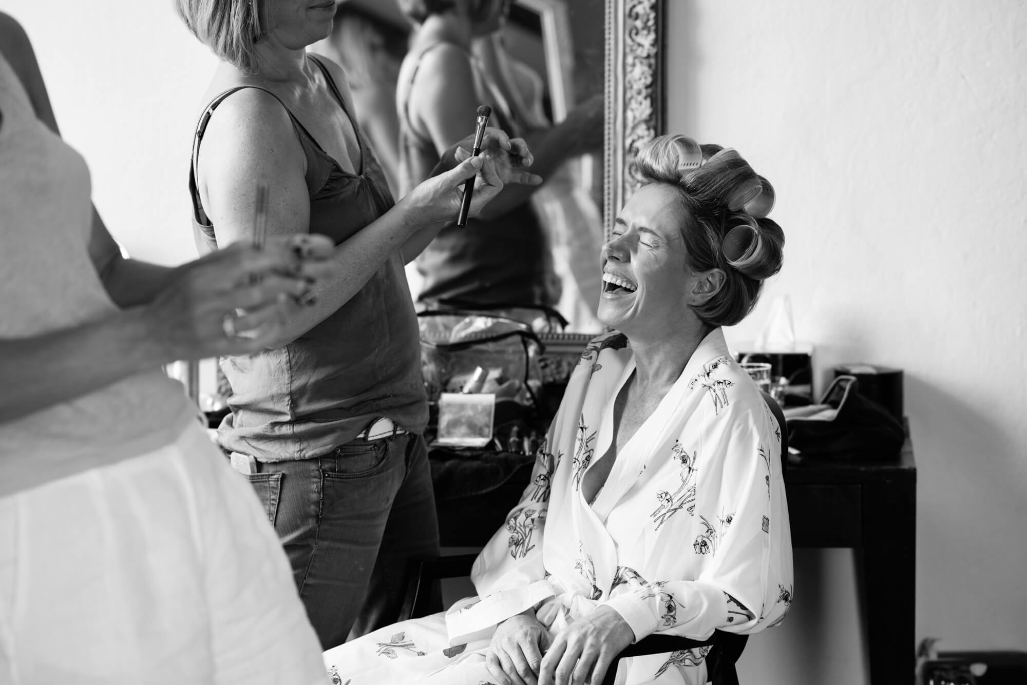 A bride laughing whilst having her hair and make up done by Laura Cawte at Chateau Rigaud