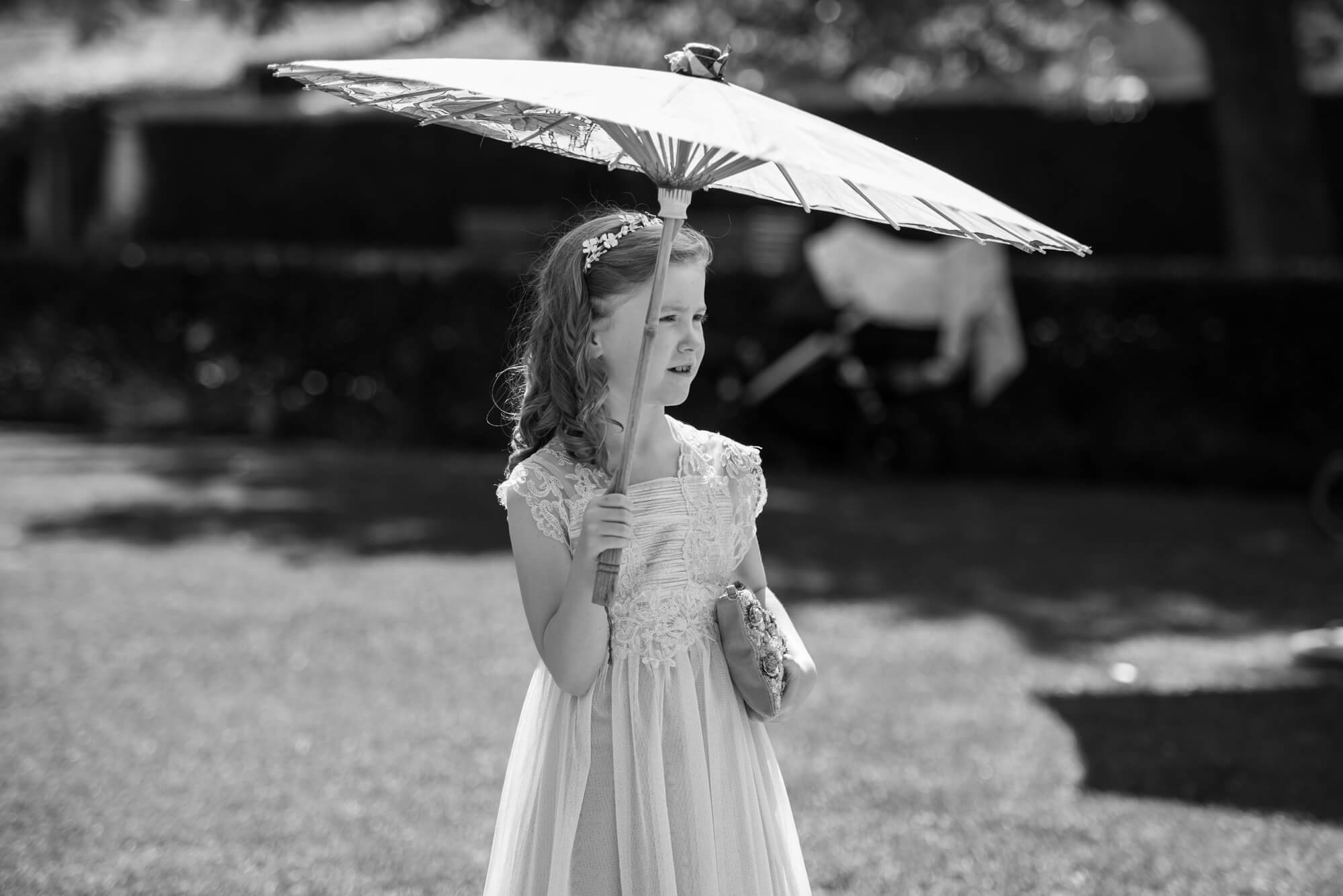 A flower girl holding a parasol in the sunshine