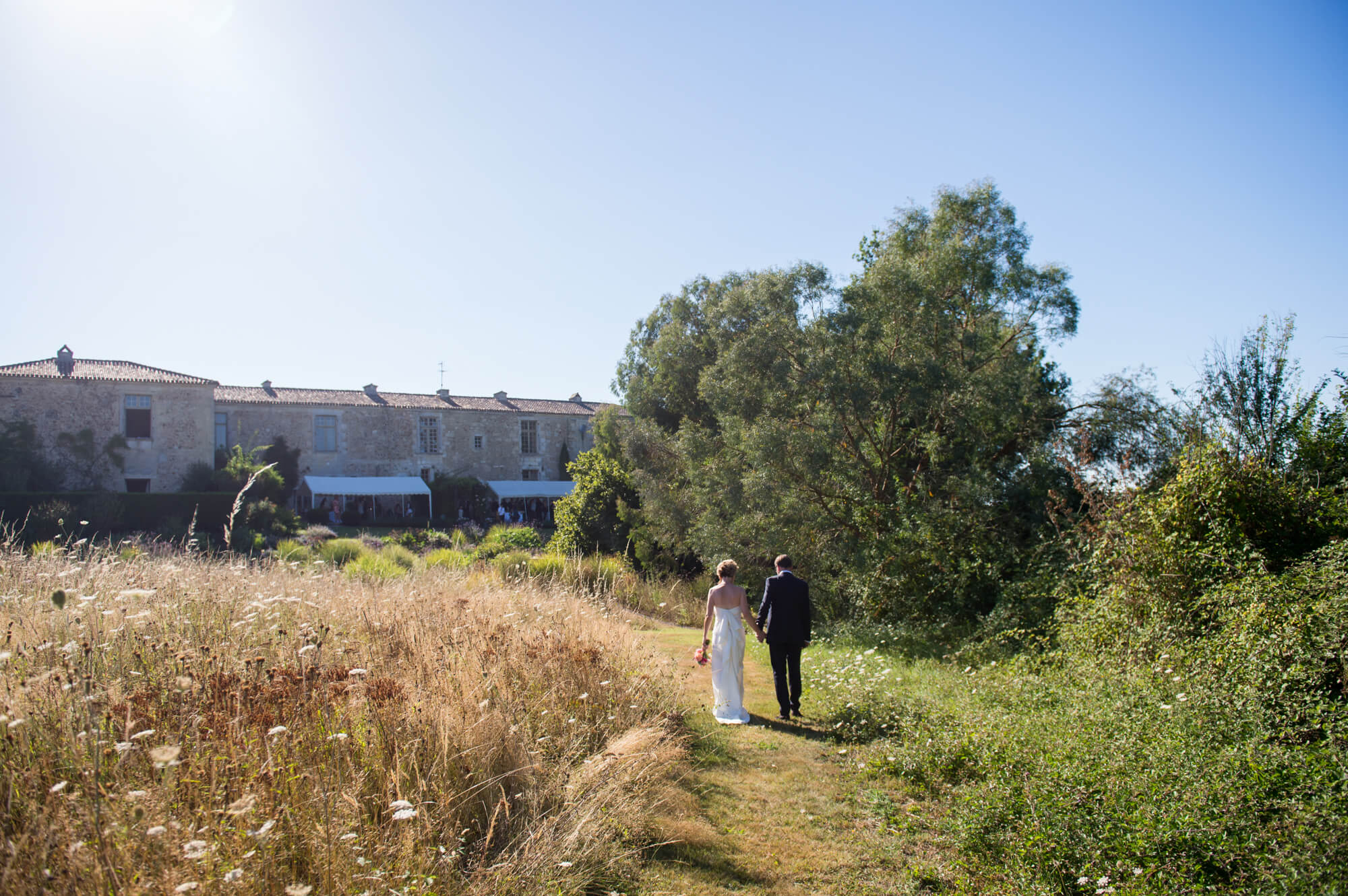 bride and groom walking through the meadow at chateau rigaud