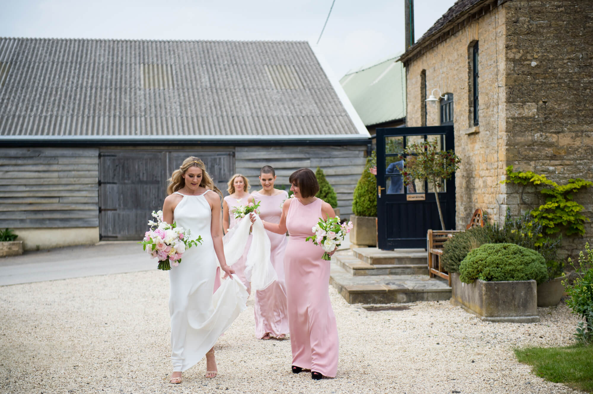 A bride wearing a Charlie Brear wedding dress, walking alongside her bridesmaids
