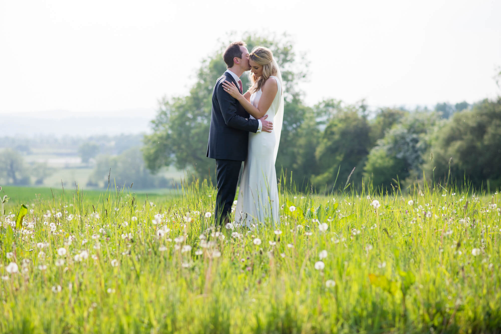 A bride and groom kissing in the grounds of Merriscourt in the Oxfordshire countryside 