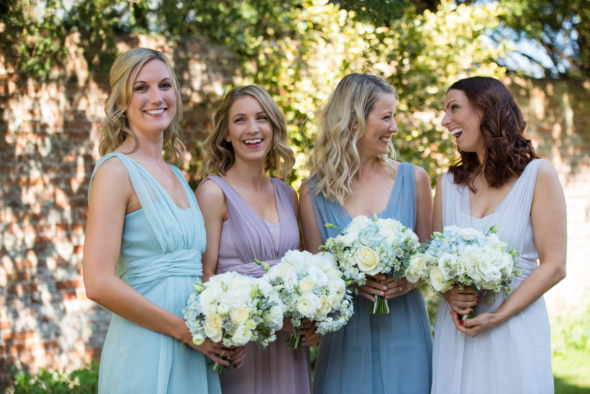 The bridesmaids standing together smiling and holding wedding bouquets