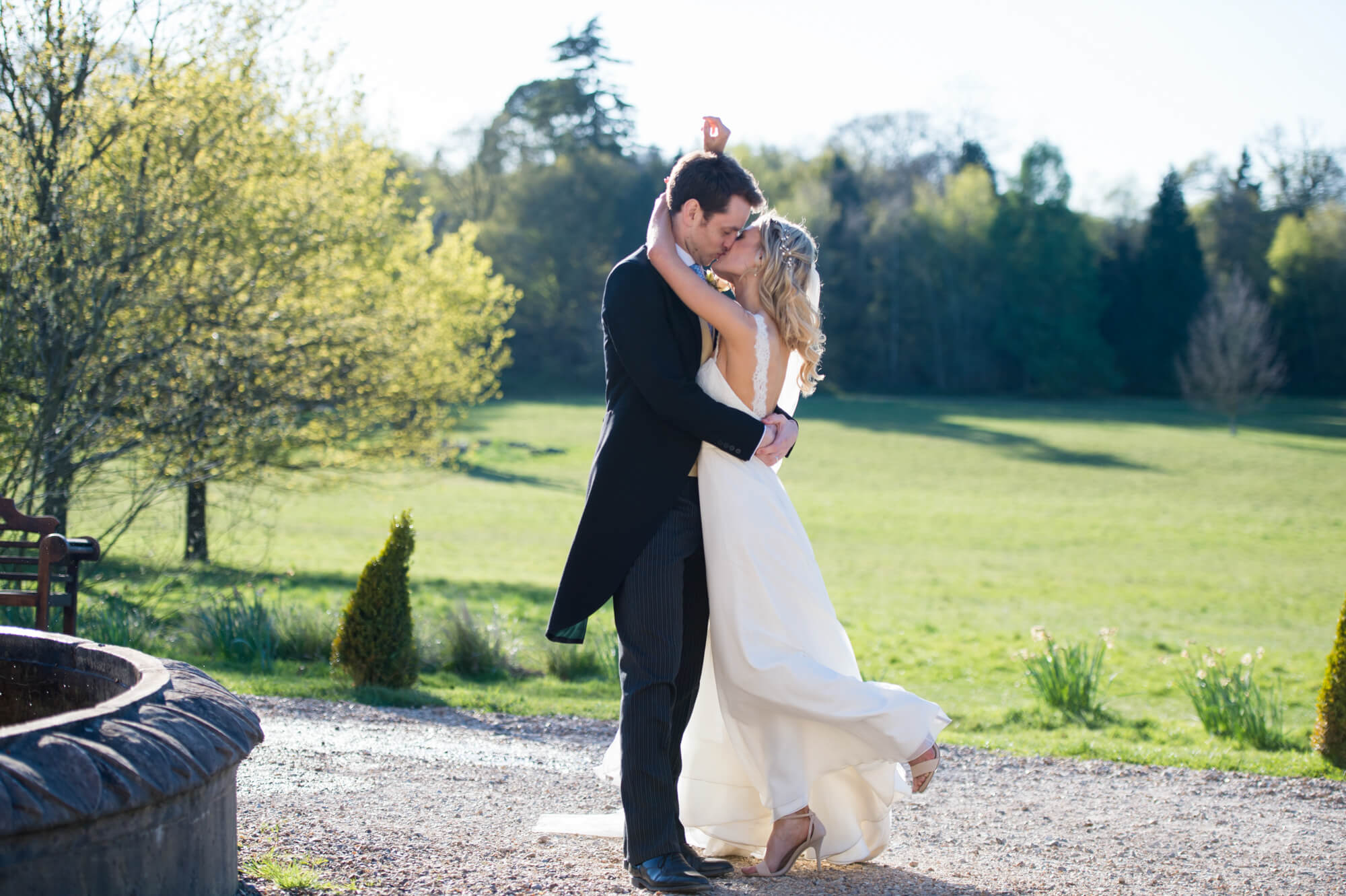 A newly married couple kissing next to the fountain at Botleys Mansion