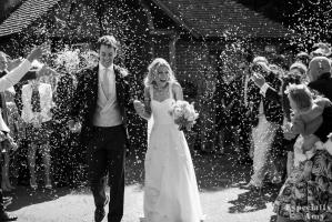 bride and groom with confetti outside the church in surrey before botleys mansion wedding reception